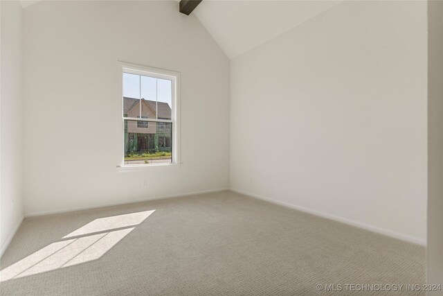 carpeted empty room featuring vaulted ceiling with beams