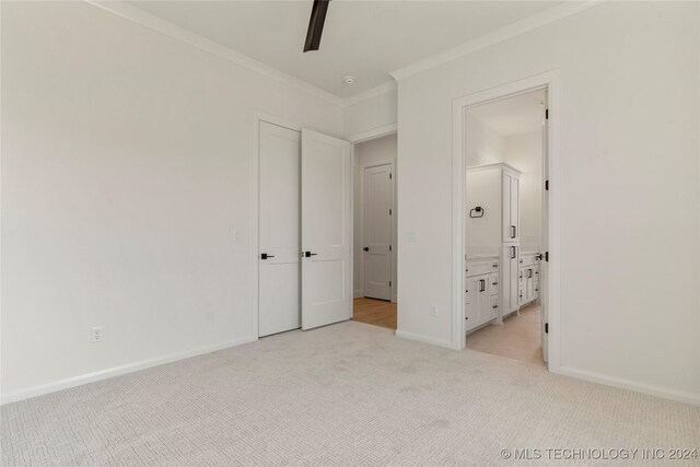 unfurnished bedroom featuring ensuite bathroom, ceiling fan, ornamental molding, and light carpet