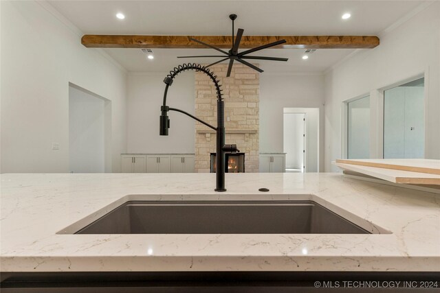 interior details featuring light stone countertops, ceiling fan, crown molding, and sink