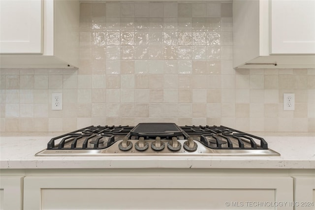 kitchen featuring light stone countertops, decorative backsplash, white cabinets, and stainless steel gas stovetop