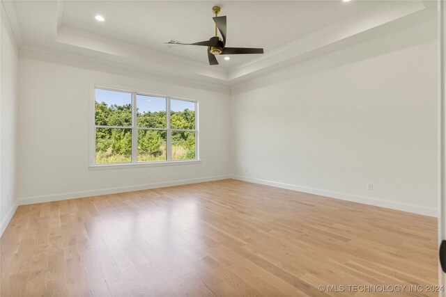 unfurnished room featuring ceiling fan, light hardwood / wood-style floors, ornamental molding, and a tray ceiling