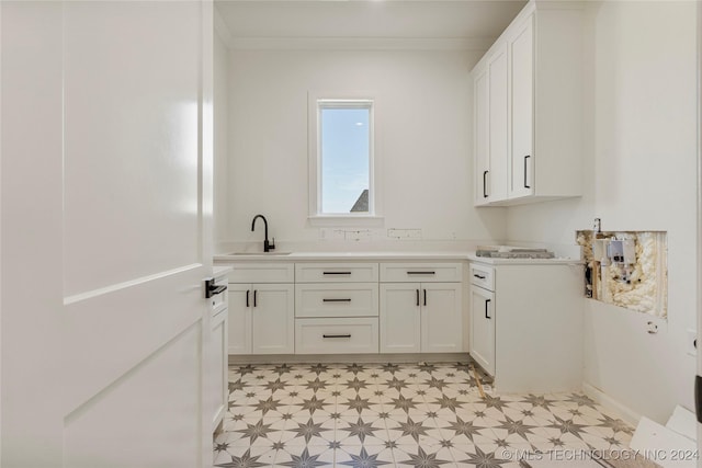 clothes washing area with sink and crown molding