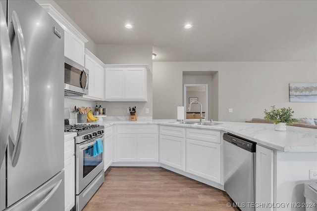 kitchen featuring white cabinets, sink, light wood-type flooring, appliances with stainless steel finishes, and kitchen peninsula