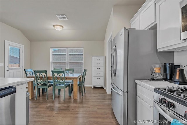 kitchen with dark hardwood / wood-style floors, white cabinetry, appliances with stainless steel finishes, and vaulted ceiling