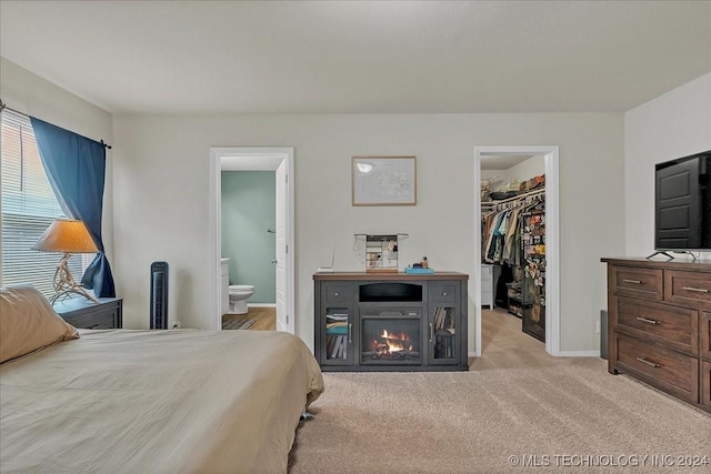 carpeted bedroom featuring a walk in closet, ensuite bathroom, and a closet