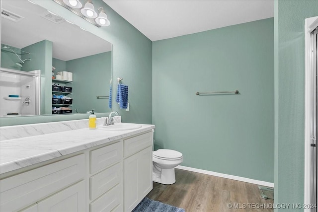 bathroom with a shower, vanity, hardwood / wood-style flooring, and toilet