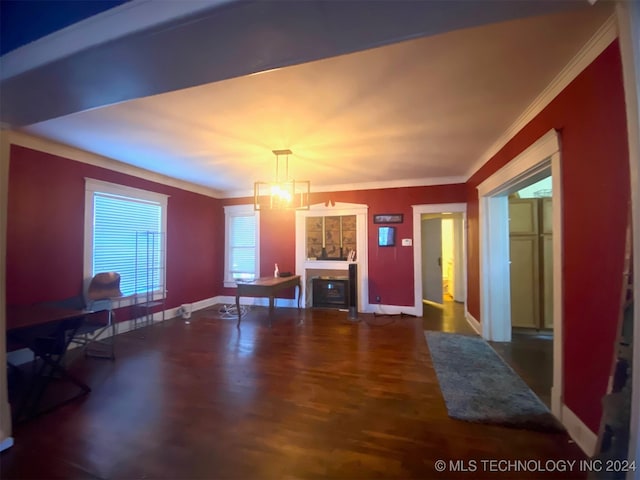 unfurnished living room with dark hardwood / wood-style flooring, an inviting chandelier, and ornamental molding