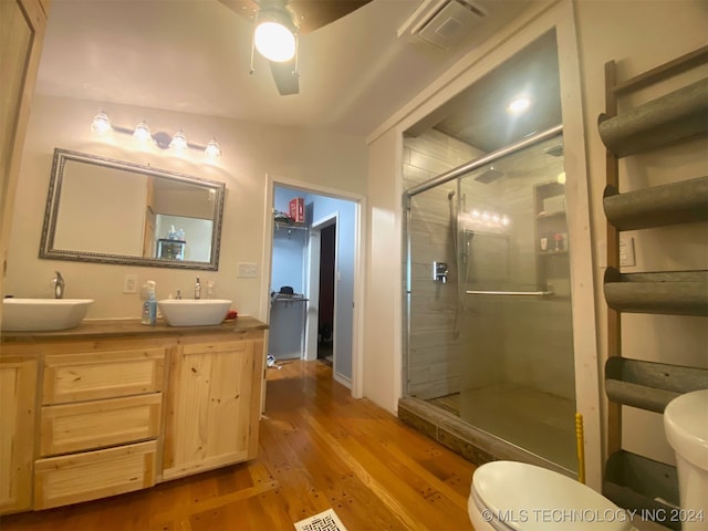 bathroom with vanity, hardwood / wood-style flooring, ceiling fan, toilet, and an enclosed shower