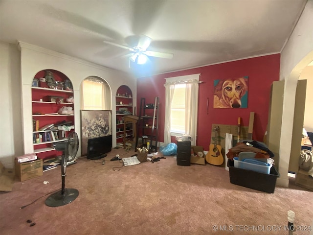 interior space with carpet flooring, ceiling fan, built in features, and ornamental molding