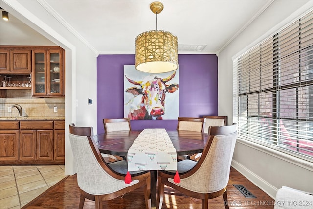 tiled dining area featuring sink and crown molding