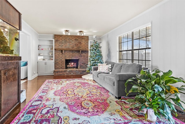 living room featuring a fireplace, built in shelves, crown molding, and dark wood-type flooring