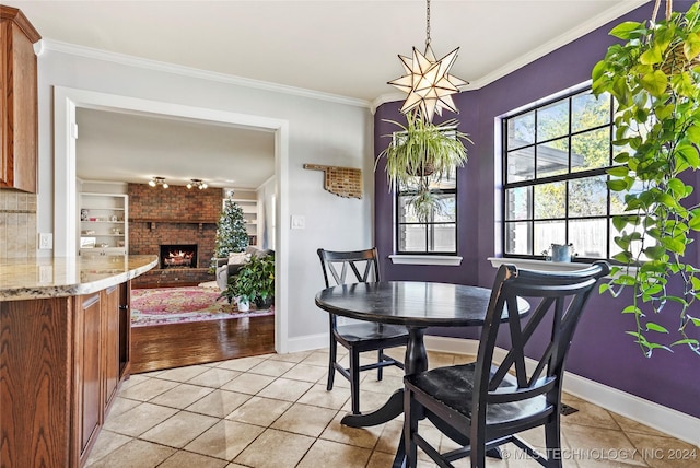 dining room with a fireplace, light tile patterned flooring, and ornamental molding