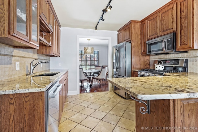 kitchen with appliances with stainless steel finishes, tasteful backsplash, light stone counters, sink, and light tile patterned floors