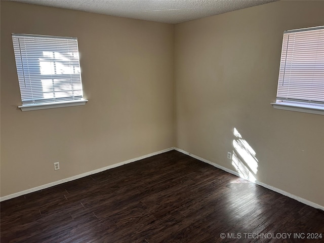 spare room featuring a textured ceiling and dark wood-type flooring