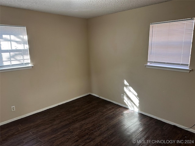 spare room with dark wood-type flooring and a textured ceiling