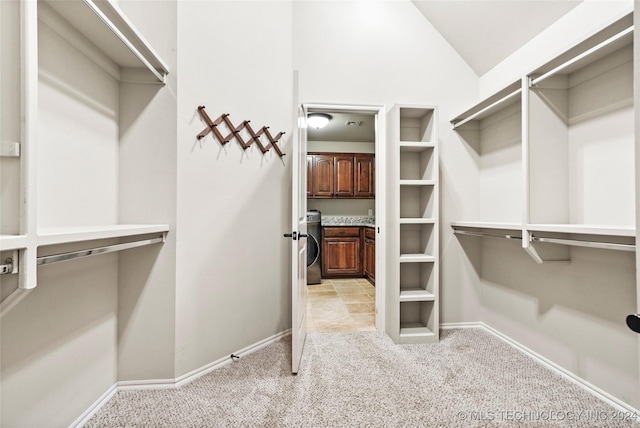 walk in closet with light colored carpet, washer / dryer, and vaulted ceiling