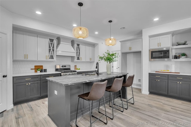 kitchen with visible vents, gray cabinets, appliances with stainless steel finishes, custom exhaust hood, and a sink