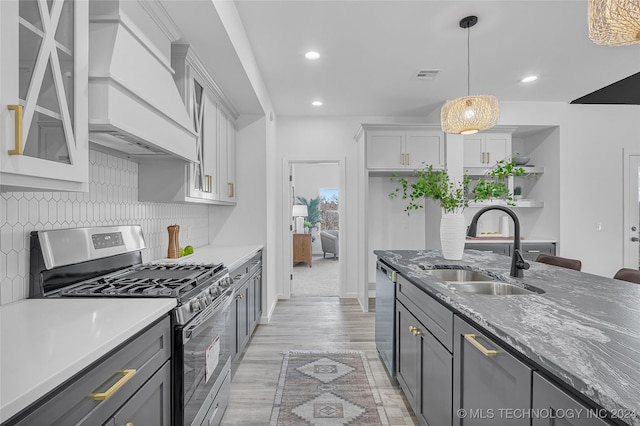 kitchen featuring appliances with stainless steel finishes, premium range hood, gray cabinetry, sink, and pendant lighting