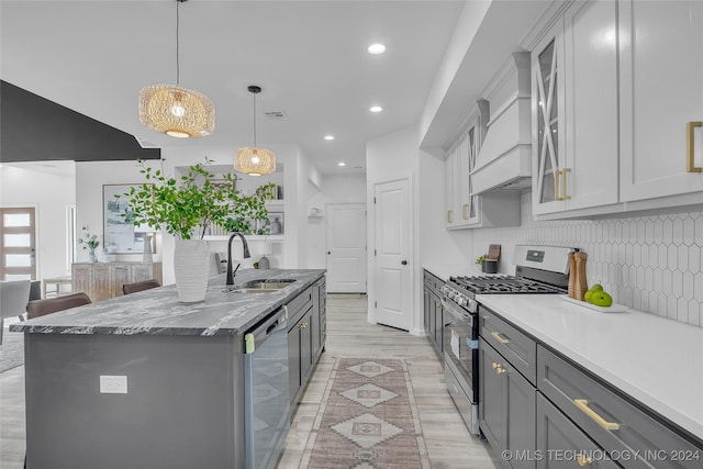 kitchen featuring stainless steel appliances, sink, gray cabinets, hanging light fixtures, and an island with sink