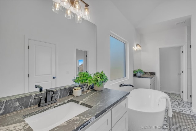 bathroom featuring plenty of natural light, lofted ceiling, a soaking tub, and vanity