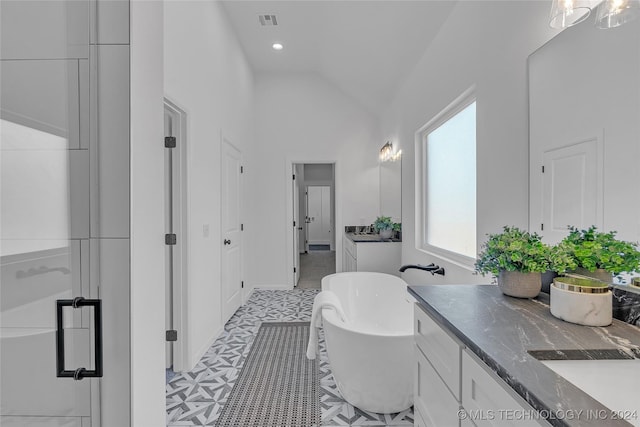 bathroom with a washtub, vanity, and vaulted ceiling