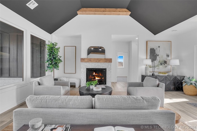 living room with vaulted ceiling with beams, hardwood / wood-style floors, and a fireplace