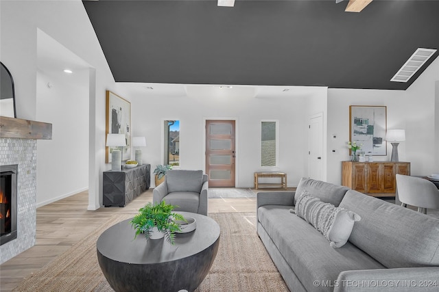 living room with light wood-type flooring and a tiled fireplace