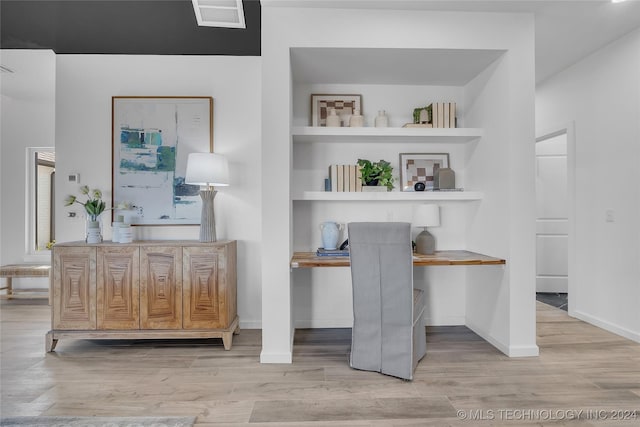 home office featuring built in shelves and light hardwood / wood-style flooring