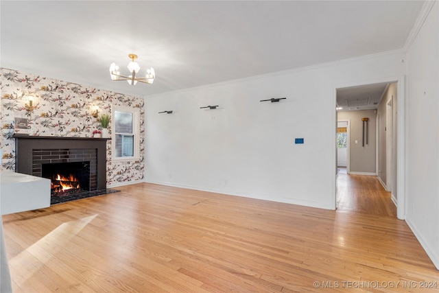 unfurnished living room with a notable chandelier, crown molding, a fireplace, and light hardwood / wood-style flooring