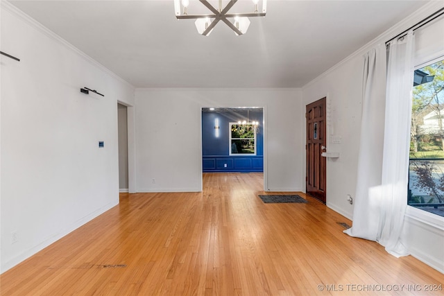 unfurnished living room featuring light hardwood / wood-style flooring, ornamental molding, and an inviting chandelier