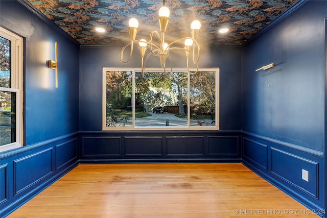 unfurnished dining area featuring light hardwood / wood-style floors, ornamental molding, and a notable chandelier