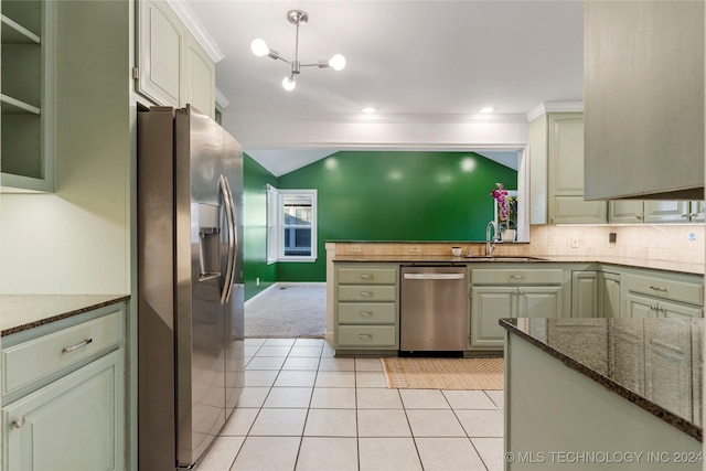 kitchen with appliances with stainless steel finishes, ornamental molding, dark stone counters, light colored carpet, and sink