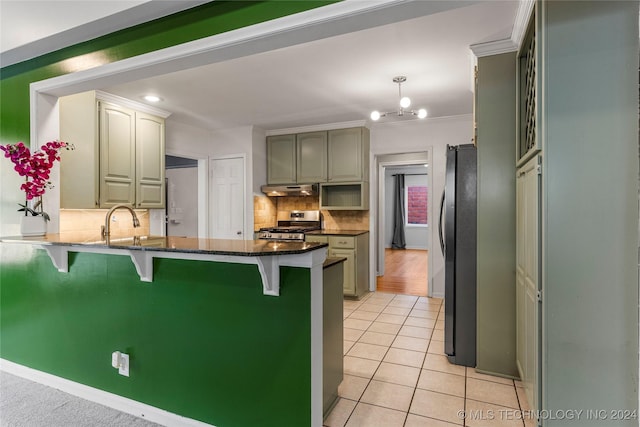 kitchen with appliances with stainless steel finishes, a kitchen bar, decorative backsplash, light tile patterned floors, and ornamental molding