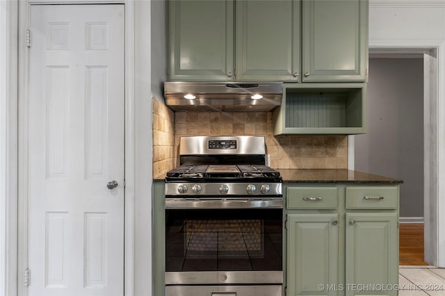 kitchen with tasteful backsplash, green cabinets, stainless steel range with gas cooktop, dark stone countertops, and light tile patterned floors