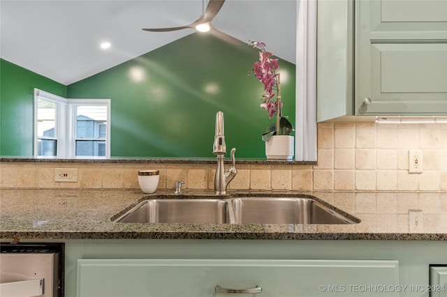 kitchen featuring ceiling fan, sink, tasteful backsplash, dark stone countertops, and vaulted ceiling