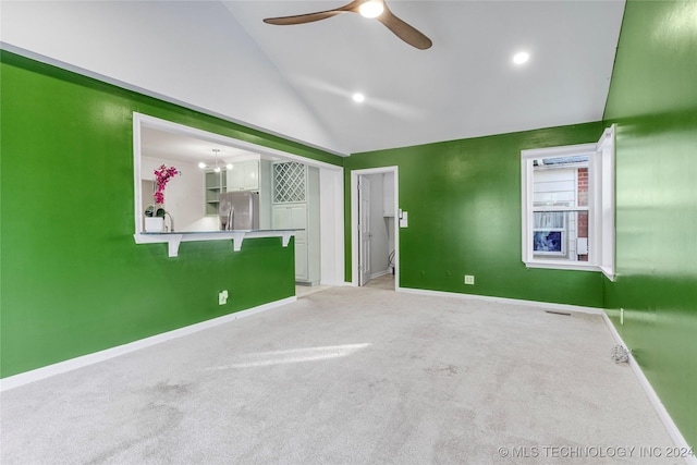 carpeted spare room with ceiling fan with notable chandelier and vaulted ceiling