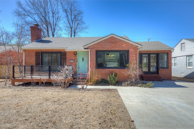 view of front of house with a shingled roof, french doors, brick siding, and a chimney