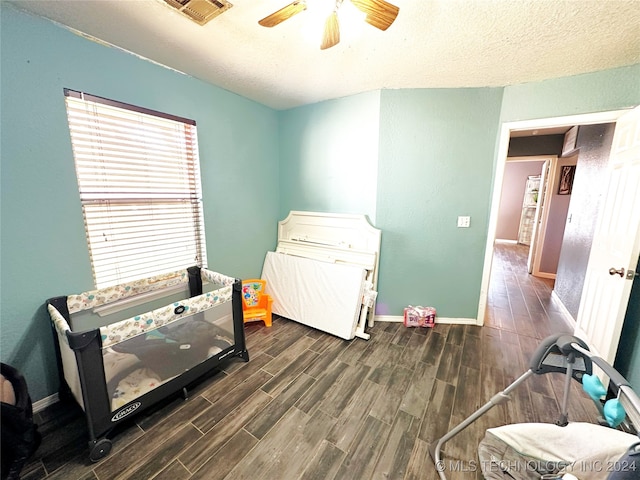 bedroom with a textured ceiling, ceiling fan, and dark wood-type flooring