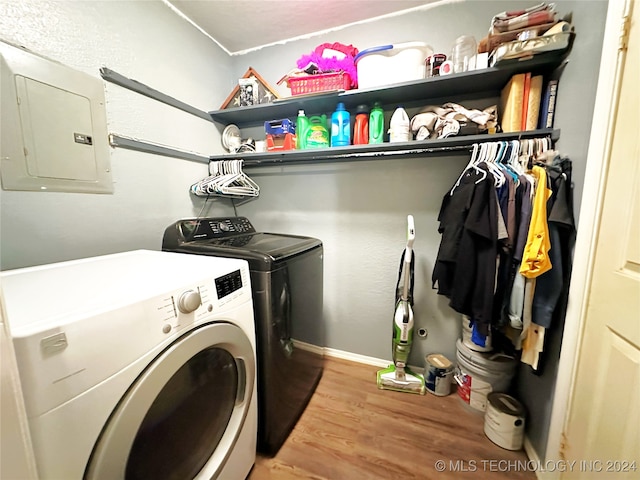 clothes washing area with light wood-type flooring, electric panel, and washing machine and clothes dryer