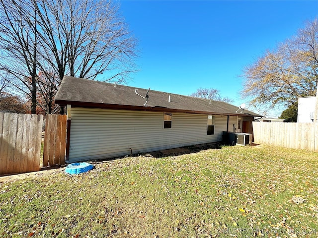 back of house featuring a yard and central air condition unit