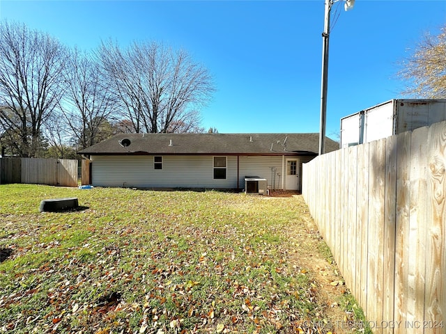 rear view of house with a lawn and central AC unit