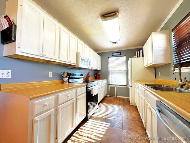 kitchen featuring a textured ceiling, white appliances, crown molding, and sink