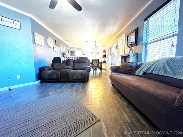 living room with ceiling fan, ornamental molding, a textured ceiling, and hardwood / wood-style flooring