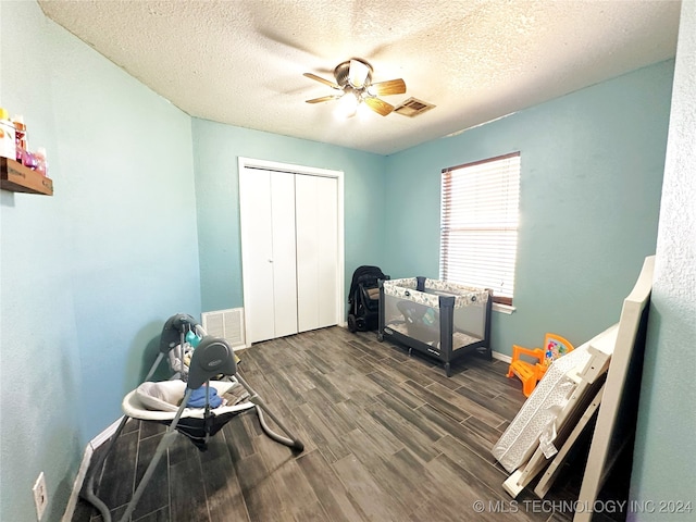 miscellaneous room with ceiling fan, dark wood-type flooring, and a textured ceiling