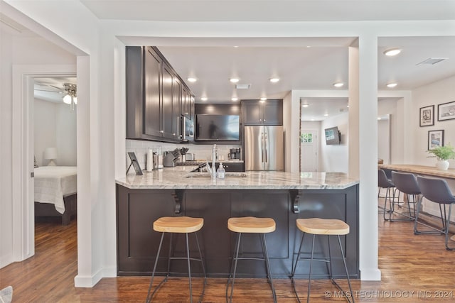 kitchen with tasteful backsplash, light stone countertops, dark wood-type flooring, and stainless steel appliances