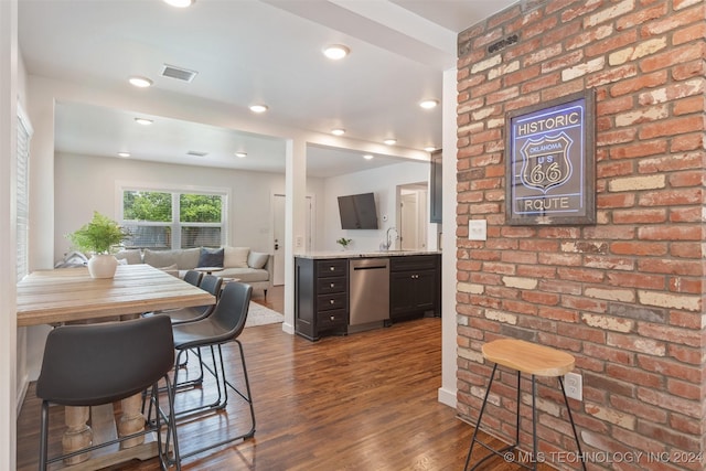 dining room with brick wall, dark hardwood / wood-style flooring, and sink