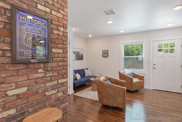 living room with brick wall and dark hardwood / wood-style floors