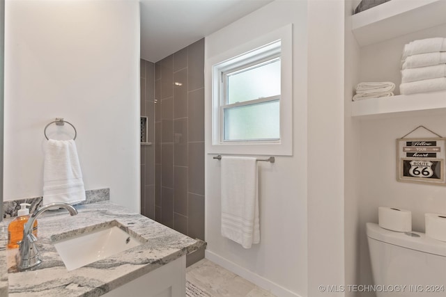 bathroom featuring vanity, toilet, and tiled shower