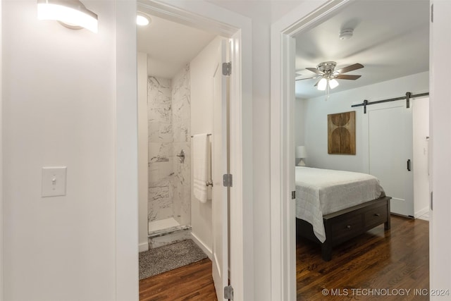 bedroom with a barn door, dark hardwood / wood-style flooring, and connected bathroom