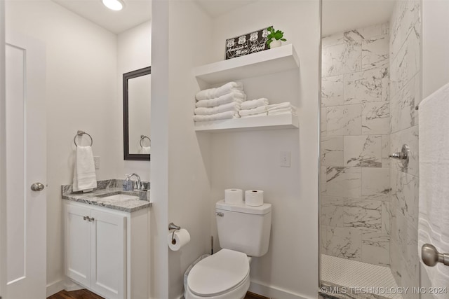 bathroom with a tile shower, vanity, and toilet